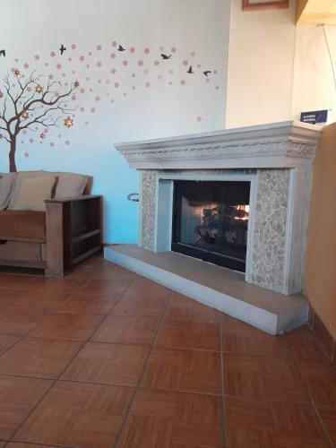 a living room with a fireplace with a tree on the wall at Casa de Ana in Tijuana