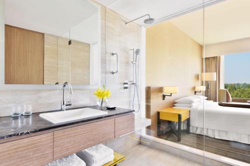 a bathroom with a sink and a large mirror at Courtyard by Marriott Bengaluru Outer Ring Road in Bangalore