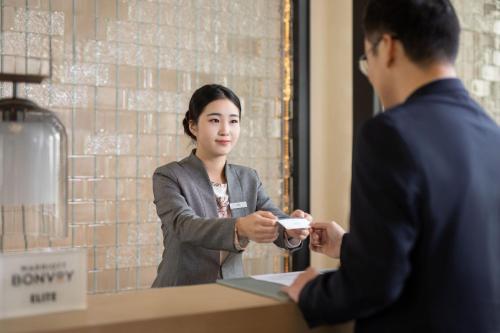 a woman standing at a counter talking to a man at Fairfield by Marriott Bijie in Bijie