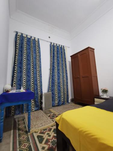 1 dormitorio con cortinas azules y amarillas y 1 cama en Dar mima baya, en Túnez