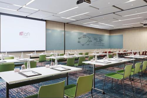 a conference room with tables and chairs and a projection screen at Aloft Beijing Huairou in Huairou