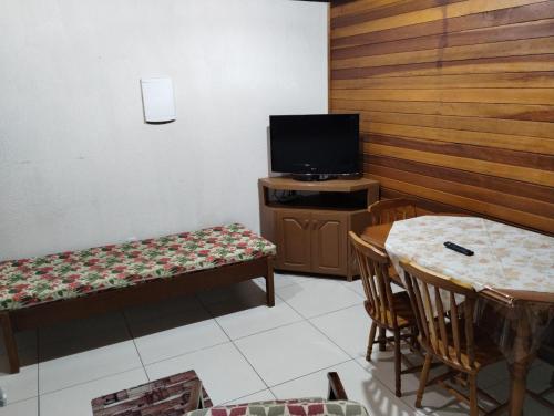 a living room with a tv and a table and chairs at Flat Theobald in Três Coroas