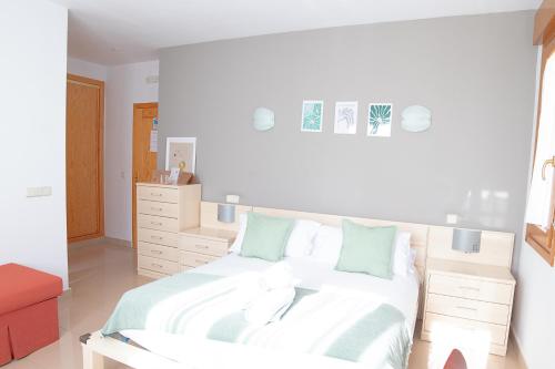 una camera da letto con un letto con lenzuola bianche e cuscini verdi di Hostal-Casa Rural Rosa-Nonna a Sigüenza