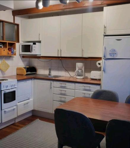 a kitchen with a table and a white refrigerator at Loma-asunto Tahkon ytimessä in Kuopio