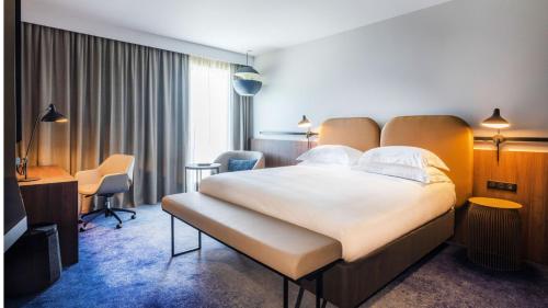 a hotel room with a large bed and a desk at Crowne Plaza - Nice - Grand Arenas by IHG in Nice