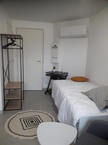 a white bedroom with a bed and a table at Studio moderne bords de Loire in Juigné-sur-Loire