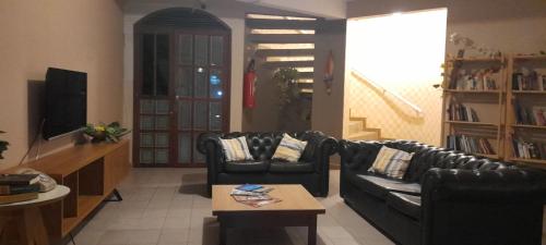 a living room with two black leather chairs and a coffee table at Pousada Casarão 2030 in Natal