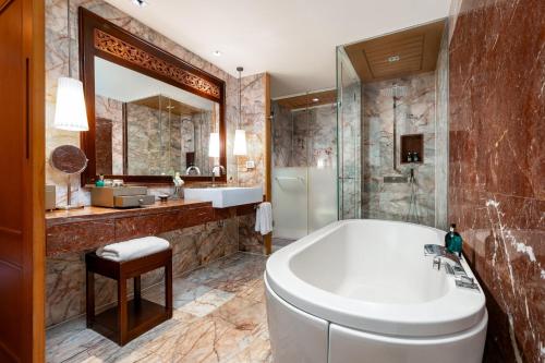 a bathroom with a tub and a large mirror at Centara Grand Beach Resort Phuket - SHA Plus in Karon Beach