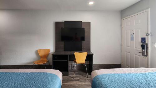 a bedroom with two chairs and a desk with a television at Motel 6-Galveston, TX in Galveston