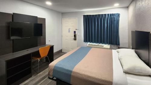 um quarto com uma cama, uma secretária e uma televisão em Motel 6-Galveston, TX em Galveston
