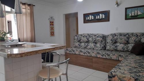 Una sala de estar con un sofá y una cocina con encimera. en Apartamento em Ubatuba- centro - apartamento 2 quartos com ar cond, en Ubatuba