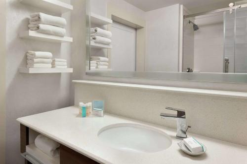 uma casa de banho com lavatório, espelho e toalhas em Hampton Inn Denville-Rockaway-Parsippany em Denville