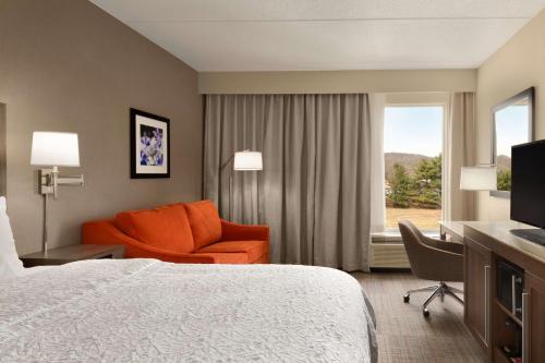 a hotel room with a bed and a chair and a window at Hampton Inn Denville-Rockaway-Parsippany in Denville