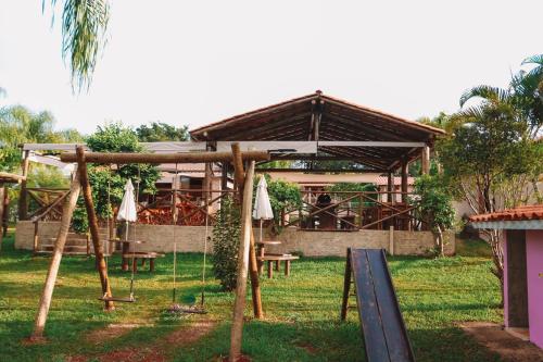 a pavilion with tables and umbrellas in a yard at Pousada Estância Mineira in Guapé