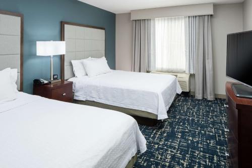a hotel room with two beds and a flat screen tv at Homewood Suites by Hilton Fresno Airport/Clovis in Clovis