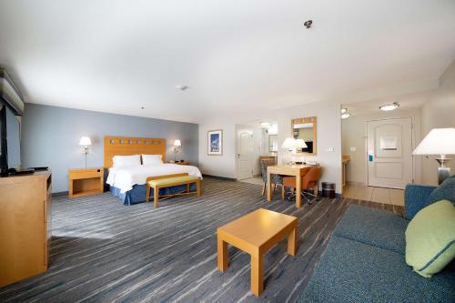 a hotel room with a bed and a living room at Hampton Inn & Suites Madera in Madera