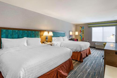 a hotel room with two beds and a window at Hampton Inn Fort Collins in Fort Collins