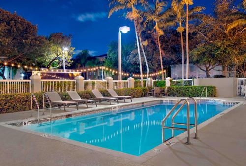 a swimming pool with lounge chairs next to a fence at Hampton Inn Ft Lauderdale Airport North Cruise Port in Fort Lauderdale
