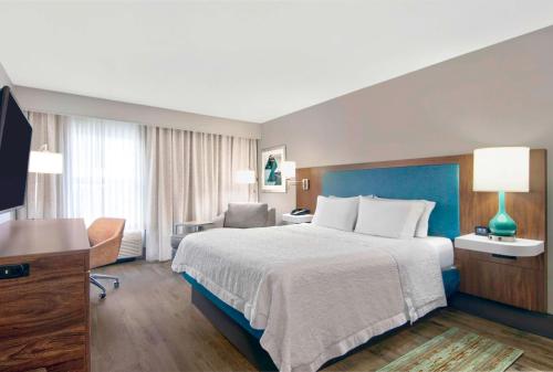 Habitación de hotel con cama grande y escritorio. en Hampton Inn Ft Lauderdale Airport North Cruise Port, en Fort Lauderdale