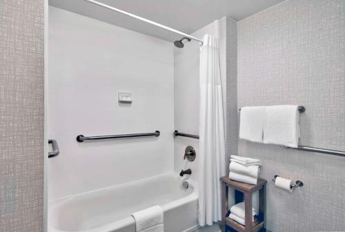 a bathroom with a tub and a shower with towels at Hampton Inn Ft Lauderdale Airport North Cruise Port in Fort Lauderdale