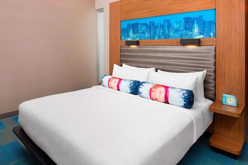 a white bed in a hotel room with a large bed at Aloft Beachwood in Beachwood
