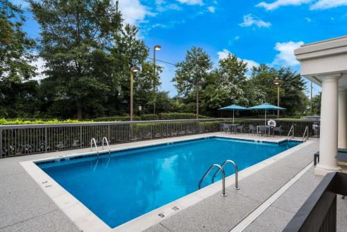 einen Pool in einem Resort mit einem Zaun und Bäumen in der Unterkunft Hampton Inn and Suites Fredericksburg in Fredericksburg