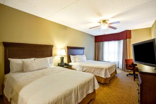 a hotel room with two beds and a flat screen tv at Homewood Suites Fredericksburg in Fredericksburg