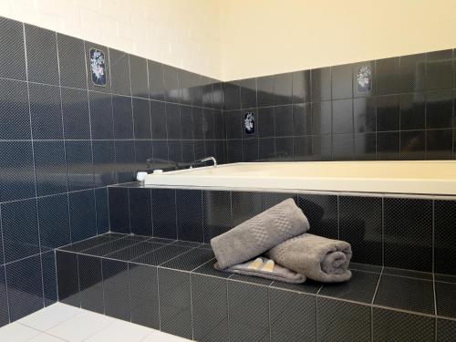 uma casa de banho com banheira e toalhas numa prateleira em Settlement Motor Inn em Deniliquin