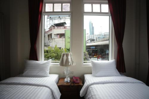 two beds in a room with a window at The Myth - Sud Sathorn in Bangkok