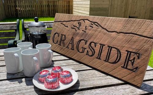 a plate of cupcakes on a table with a sign at Cragside in Callander