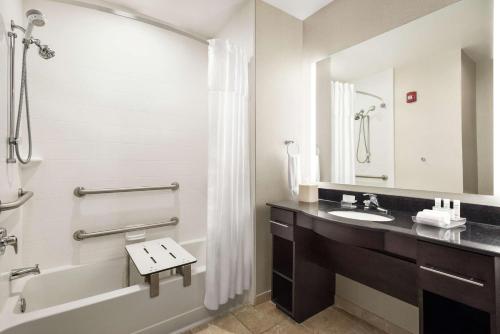 a bathroom with a sink and a tub and a mirror at Homewood Suites Fort Wayne in Fort Wayne
