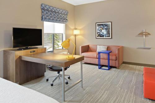 a hotel room with a desk with a television and a couch at Hampton Inn & Suites Spokane Valley in Spokane Valley