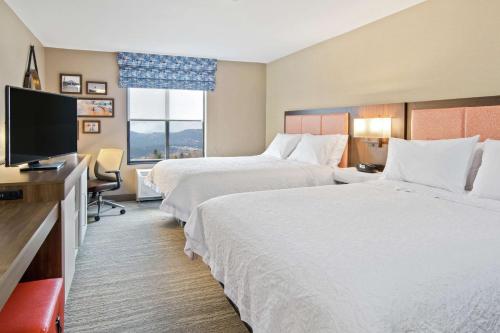 a hotel room with two beds and a flat screen tv at Hampton Inn & Suites Spokane Valley in Spokane Valley