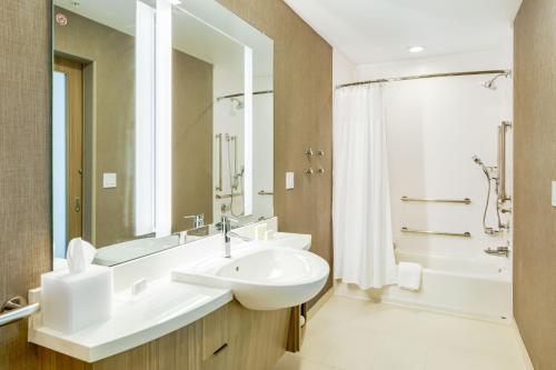 a bathroom with a sink and a tub and a mirror at SpringHill Suites by Marriott Topeka Southwest in Topeka