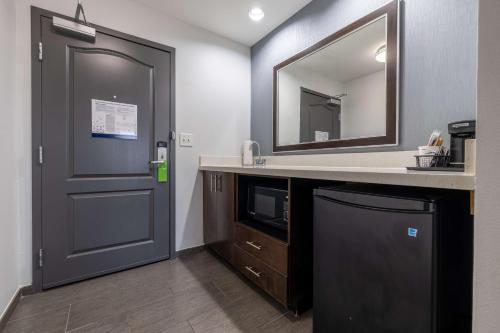 baño con lavabo, espejo y puerta en Hampton Inn & Suites Greensboro/Coliseum Area en Greensboro