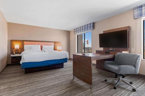 a hotel room with a bed and a desk and a television at Hampton Inn & Suites Greeley in Greeley