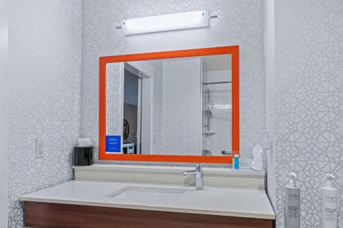 an orange mirror over a sink in a bathroom at Hampton Inn & Suites Greeley in Greeley