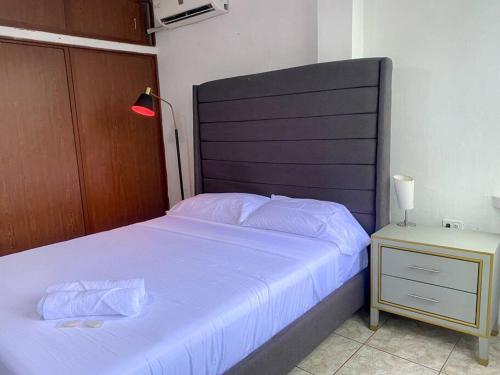 a bedroom with a white bed with a black headboard and a night stand at Moderno, grande, amplia vista, parqueo in Machala