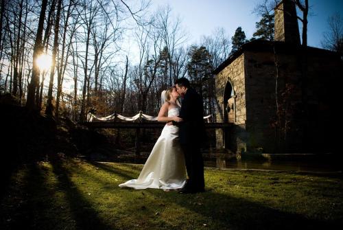 a bride and groom standing in front of a fence at Hampton Inn Greensboro Airport in Greensboro