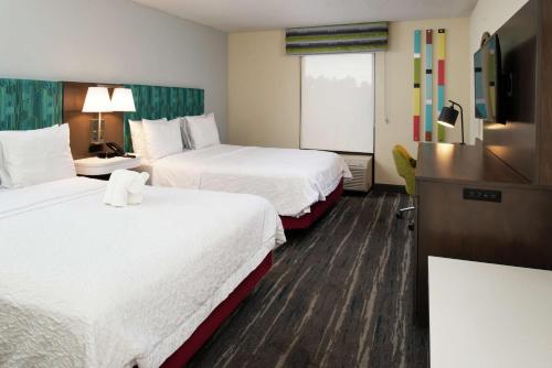 a hotel room with two beds and a flat screen tv at Hampton Inn Greensboro Airport in Greensboro