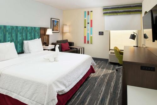 um quarto de hotel com uma cama grande e uma sala de estar em Hampton Inn Greensboro Airport em Greensboro