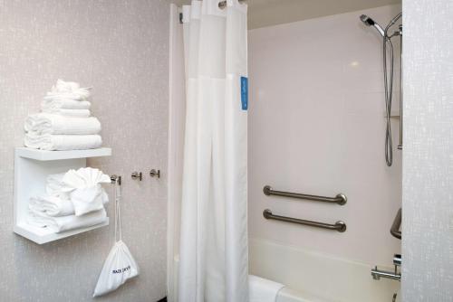 baño con ducha con cortina blanca en Hampton Inn Greensboro Airport en Greensboro