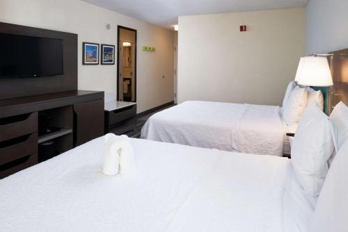 a hotel room with two beds and a flat screen tv at Hampton Inn Greensboro Airport in Greensboro
