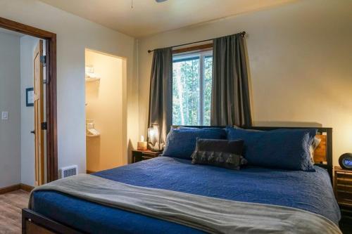 a bedroom with a blue bed with a window at Pinetree Lodge: Hot Tub Fire Pit in Athol