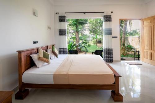 1 dormitorio con cama y ventana grande en Villa River Edge, en Weligama
