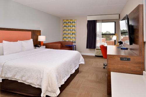 a hotel room with a large bed and a chair at Hampton Inn Henderson in Henderson