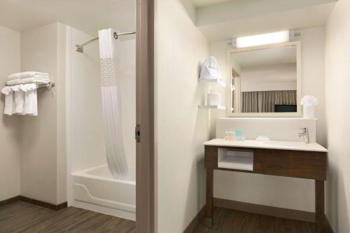 a bathroom with a tub and a sink and a mirror at Hampton Inn & Suites Hershey in Hershey