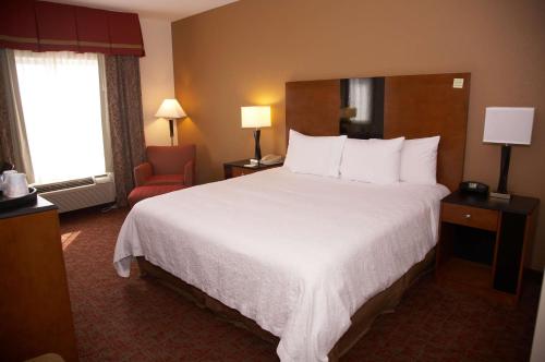 a hotel room with a large bed and a chair at Hampton Inn & Suites Hobbs in Hobbs