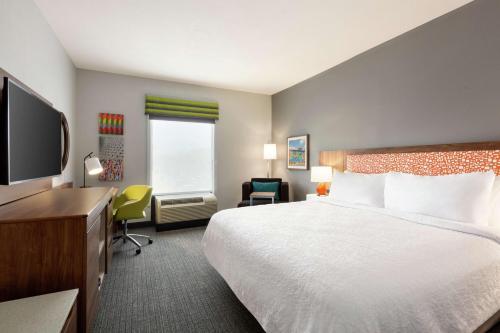 a hotel room with a bed and a flat screen tv at Hampton Inn & Suites Houston-Cypress Station in Westfield