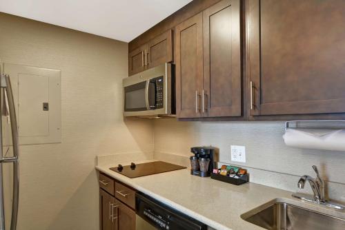 a kitchen with wooden cabinets and a sink and a microwave at Homewood Suites by Hilton Houston Near the Galleria in Houston